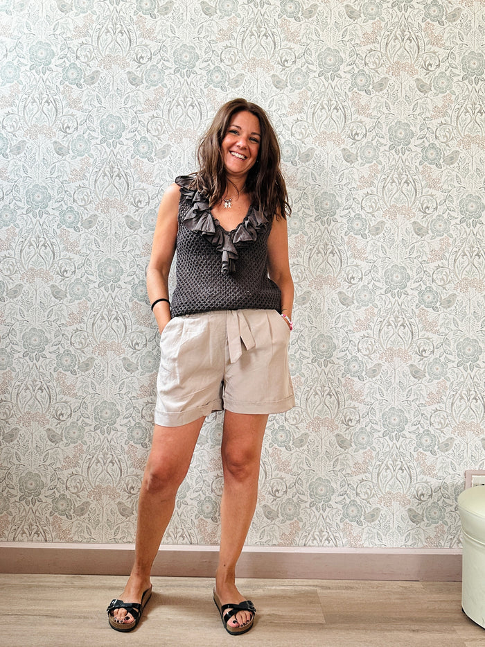 Top 100% cotone, marrone, traforato con scollo a v profondo. Dettaglio volant sullo scollo. 