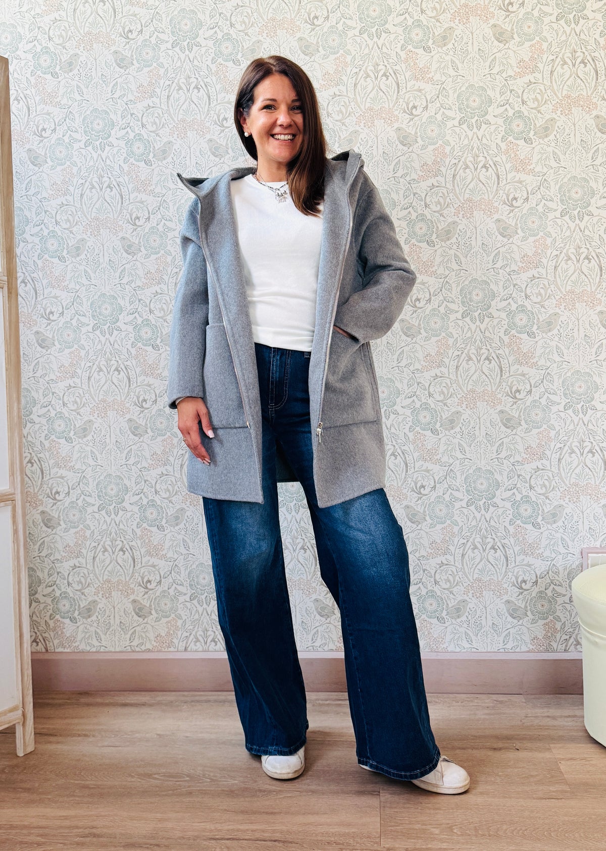 Cappotto grigio taglio dritto e ampio con chiusura zip, cappuccio e tasche sul davanti a viste e aperte. 