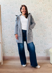 Cappotto grigio taglio dritto e ampio con chiusura zip, cappuccio e tasche sul davanti a viste e aperte. 