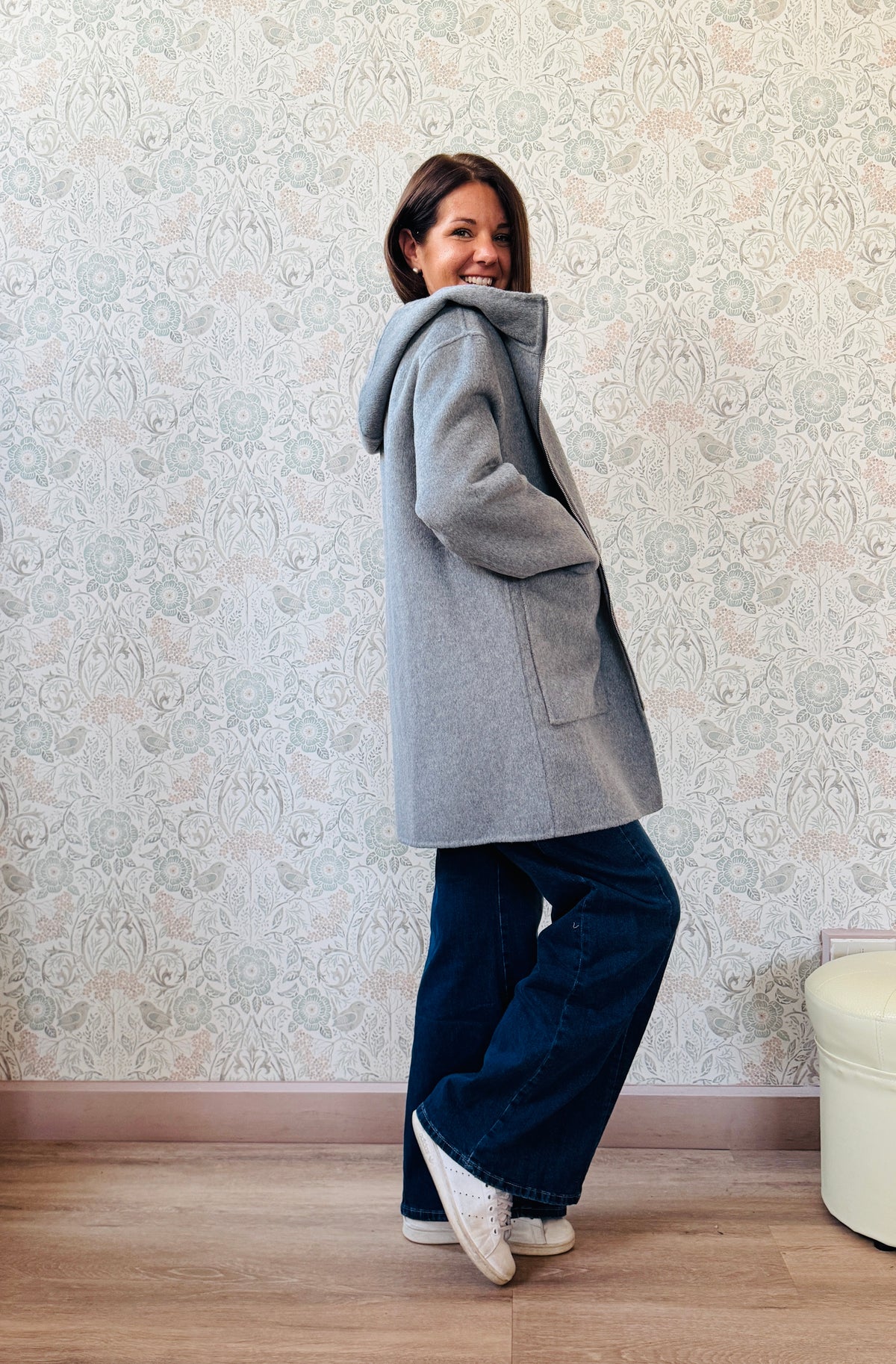 Cappotto grigio taglio dritto e ampio con chiusura zip, cappuccio e tasche sul davanti a viste e aperte. 