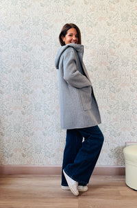 Cappotto grigio taglio dritto e ampio con chiusura zip, cappuccio e tasche sul davanti a viste e aperte. 