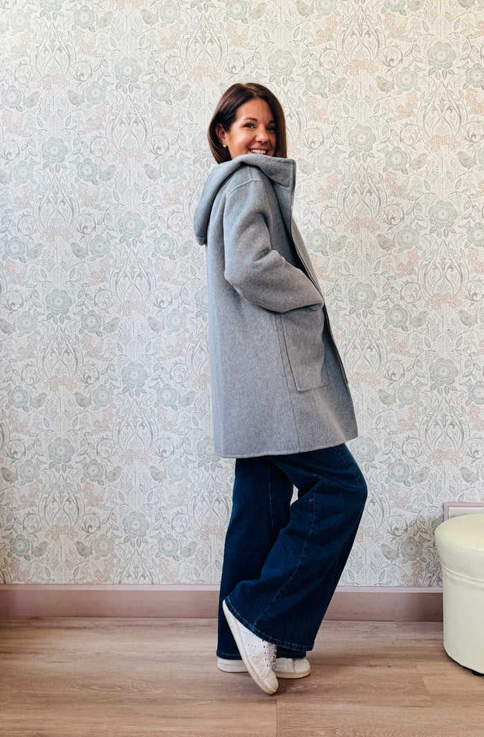 Cappotto grigio taglio dritto e ampio con chiusura zip, cappuccio e tasche sul davanti a viste e aperte. 