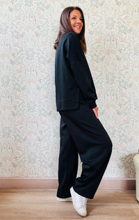 Completo composto da: Pantaloni con elastico in vita, taglio baggy e tasche sui fianchi. Felpa con scollo tondo ampia, svasata e con spacchetti laterali. 