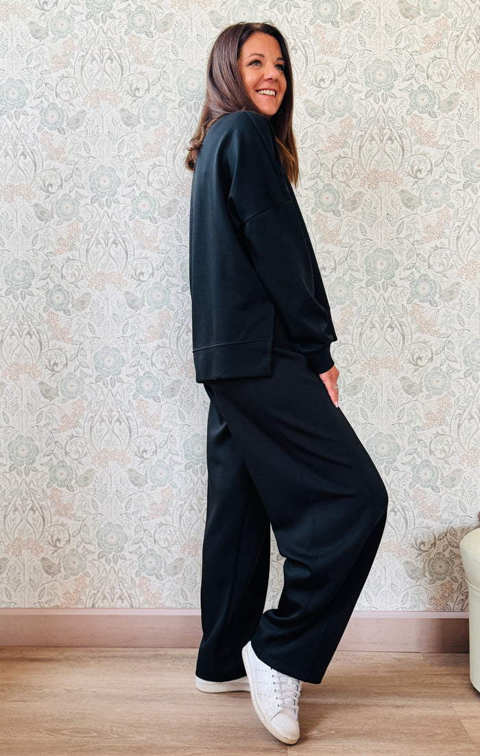 Completo composto da: Pantaloni con elastico in vita, taglio baggy e tasche sui fianchi. Felpa con scollo tondo ampia, svasata e con spacchetti laterali. 