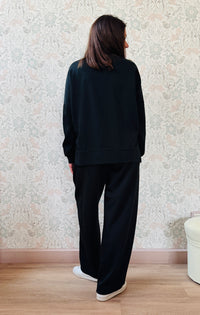 Completo composto da: Pantaloni con elastico in vita, taglio baggy e tasche sui fianchi. Felpa con scollo tondo ampia, svasata e con spacchetti laterali. 