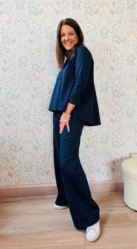 Completo composto da pantaloni con chiusura con zip e cerniera ed elastico sul retro. Taglio a palazzo. Felpa con scollo tondo dal taglio ampio e svasato. 
