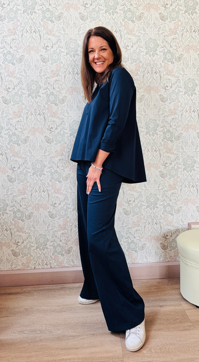 Completo composto da pantaloni con chiusura con zip e cerniera ed elastico sul retro. Taglio a palazzo. Felpa con scollo tondo dal taglio ampio e svasato. 
