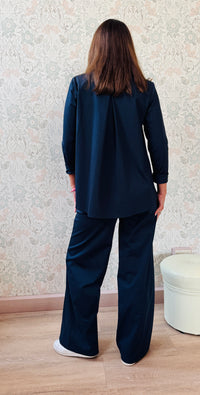 Completo composto da pantaloni con chiusura con zip e cerniera ed elastico sul retro. Taglio a palazzo. Felpa con scollo tondo dal taglio ampio e svasato. 
