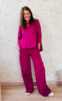 Completo composto da pantaloni con chiusura con zip e cerniera ed elastico sul retro. Taglio a palazzo. Felpa con scollo tondo dal taglio ampio e svasato.   
