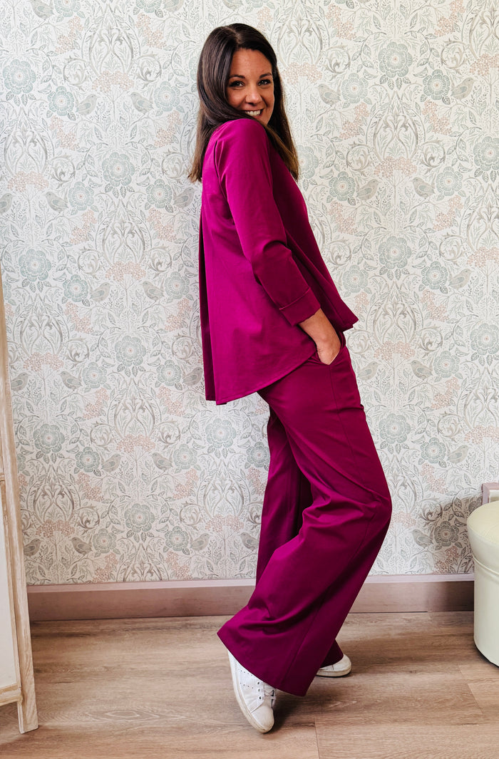 Completo composto da pantaloni con chiusura con zip e cerniera ed elastico sul retro. Taglio a palazzo. Felpa con scollo tondo dal taglio ampio e svasato.   