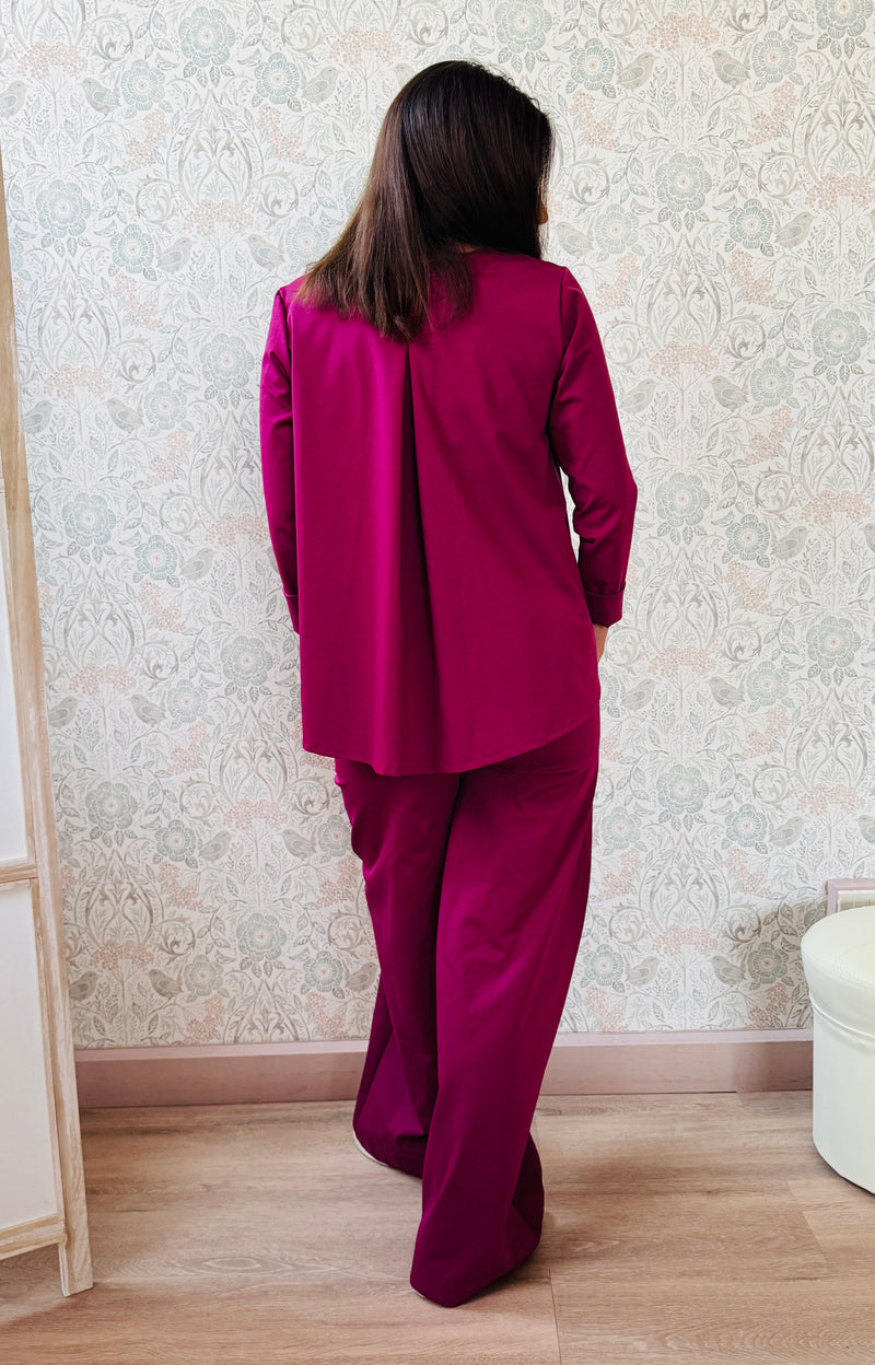 Completo composto da pantaloni con chiusura con zip e cerniera ed elastico sul retro. Taglio a palazzo. Felpa con scollo tondo dal taglio ampio e svasato.   