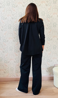 Completo composto da pantaloni con chiusura con zip e cerniera ed elastico sul retro. Taglio a palazzo. Felpa con scollo tondo dal taglio ampio e svasato.  