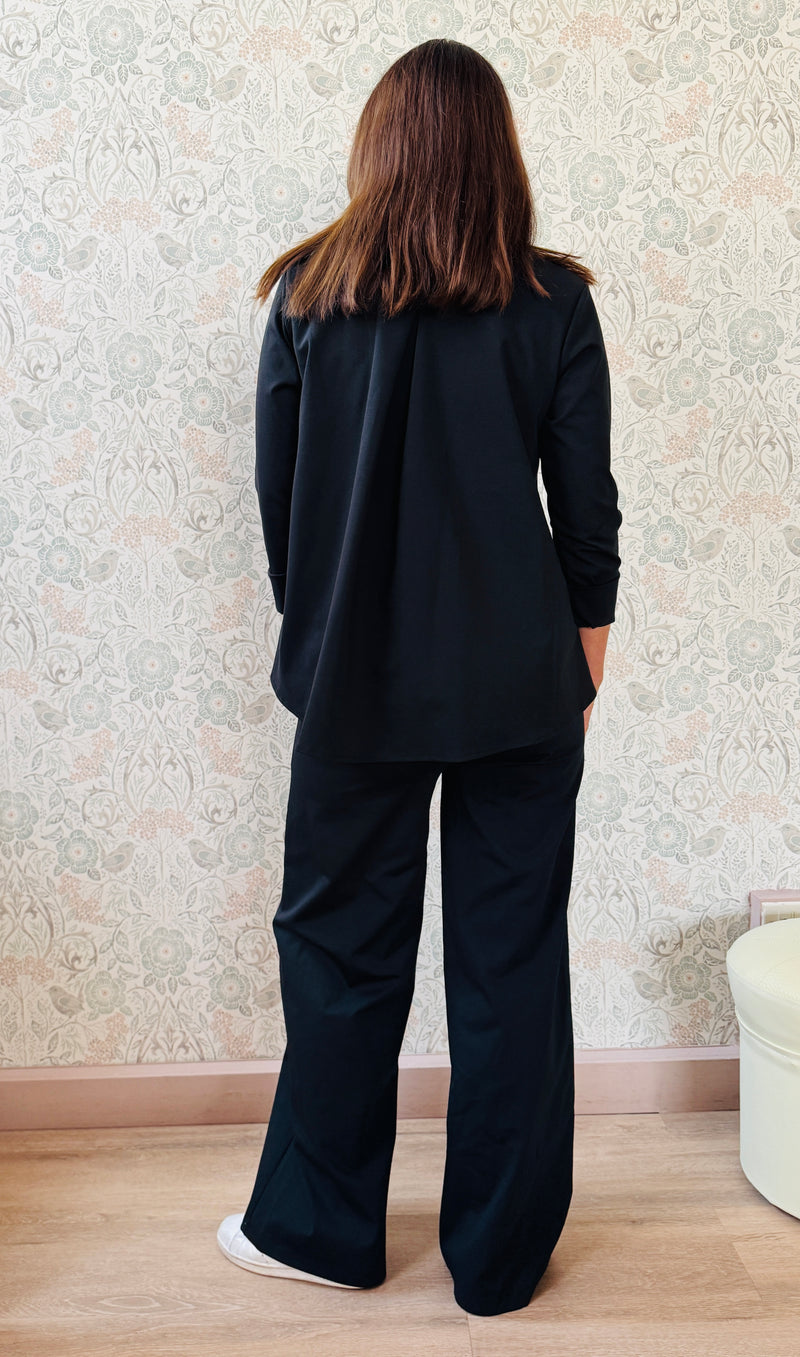 Completo composto da pantaloni con chiusura con zip e cerniera ed elastico sul retro. Taglio a palazzo. Felpa con scollo tondo dal taglio ampio e svasato.  