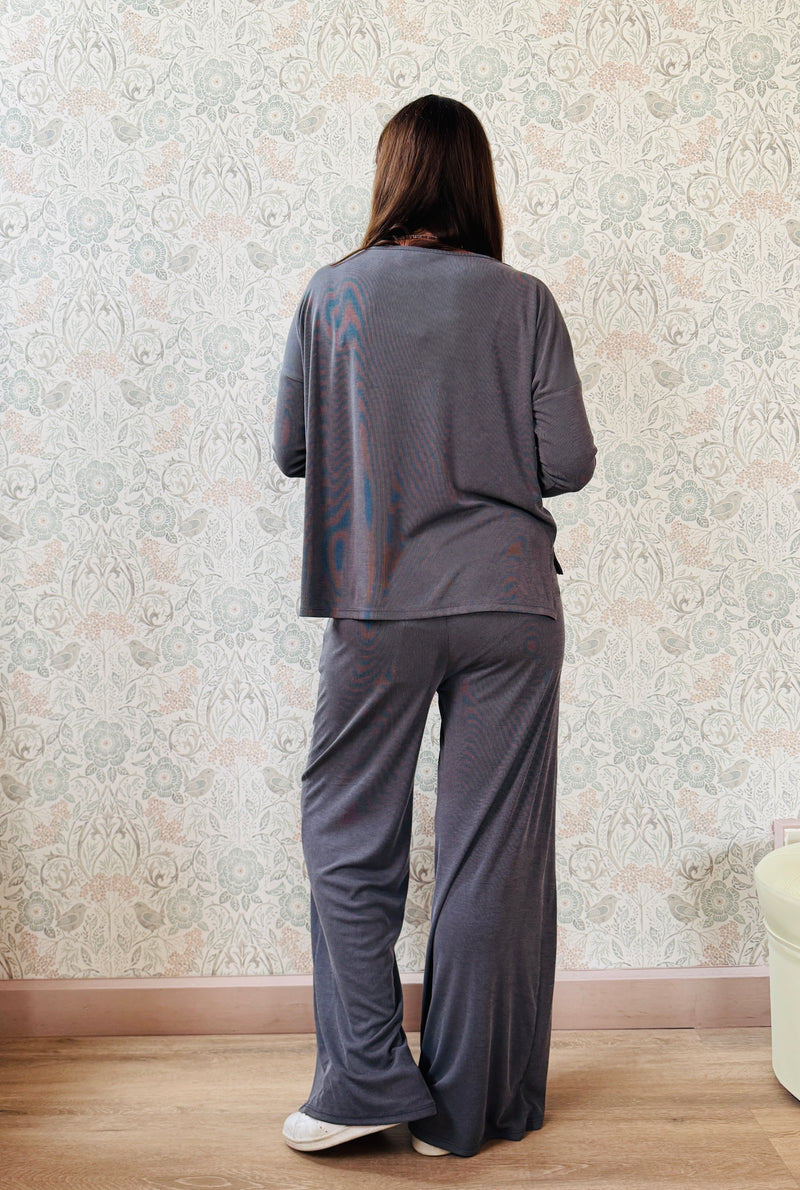 Completo a costine sottili: pantaloni ampi taglio palazzo, elastico in vita, tasche laterali; maglia scollo a barchetta, maniche lunghe e spacchetti laterali 