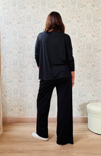 Completo a costine sottili: pantaloni ampi taglio palazzo, elastico in vita, tasche laterali; maglia scollo a barchetta, maniche lunghe e spacchetti laterali 