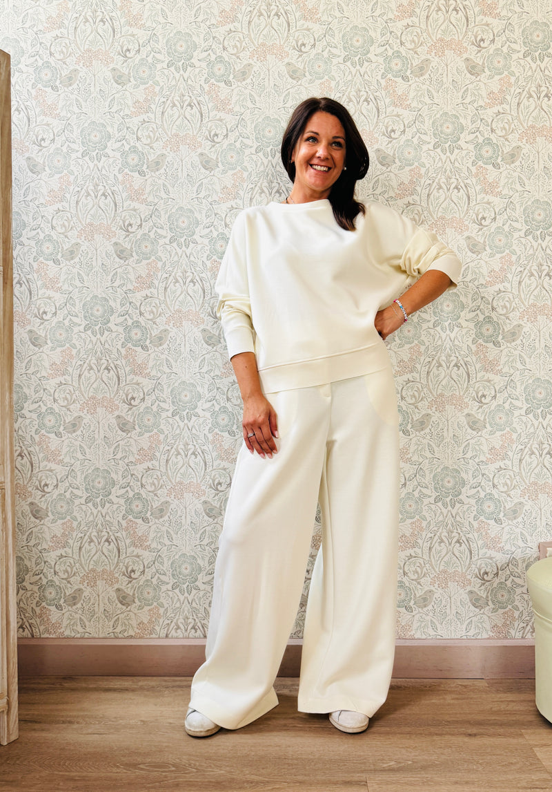 Completo da donna composto da pantaloni ampi con elastico in vita sul retro e tasche laterali; felpa con scollo tondo, manica lunga e spacchetti laterali. 