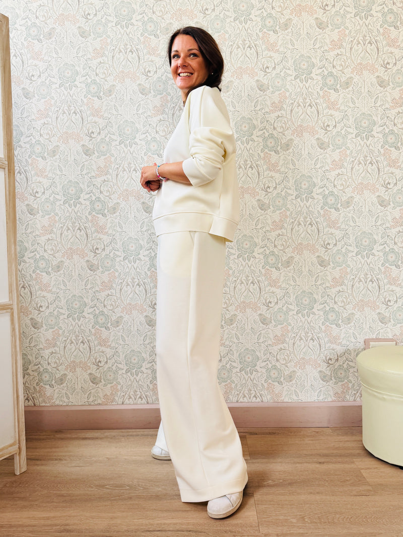 Completo da donna composto da pantaloni ampi con elastico in vita sul retro e tasche laterali; felpa con scollo tondo, manica lunga e spacchetti laterali. 