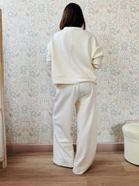 Completo da donna composto da pantaloni ampi con elastico in vita sul retro e tasche laterali; felpa con scollo tondo, manica lunga e spacchetti laterali. 