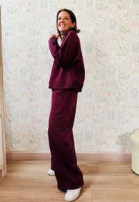 Completo da donna composto da pantaloni ampi con elastico in vita sul retro e tasche laterali; felpa con scollo tondo, manica lunga e spacchetti laterali.  