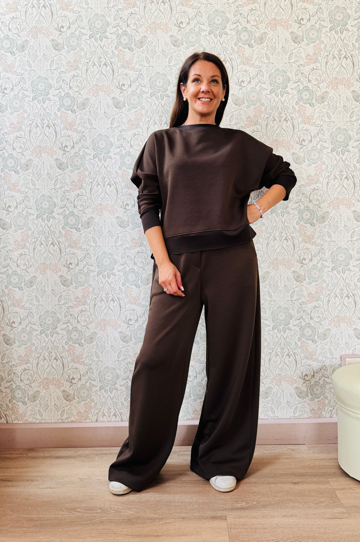Completo da donna composto da pantaloni ampi con elastico in vita sul retro e tasche laterali; felpa con scollo tondo, manica lunga e spacchetti laterali. 