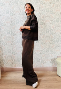 Completo da donna composto da pantaloni ampi con elastico in vita sul retro e tasche laterali; felpa con scollo tondo, manica lunga e spacchetti laterali. 