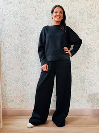 Completo da donna composto da pantaloni ampi con elastico in vita sul retro e tasche laterali; felpa con scollo tondo, manica lunga e spacchetti laterali. 