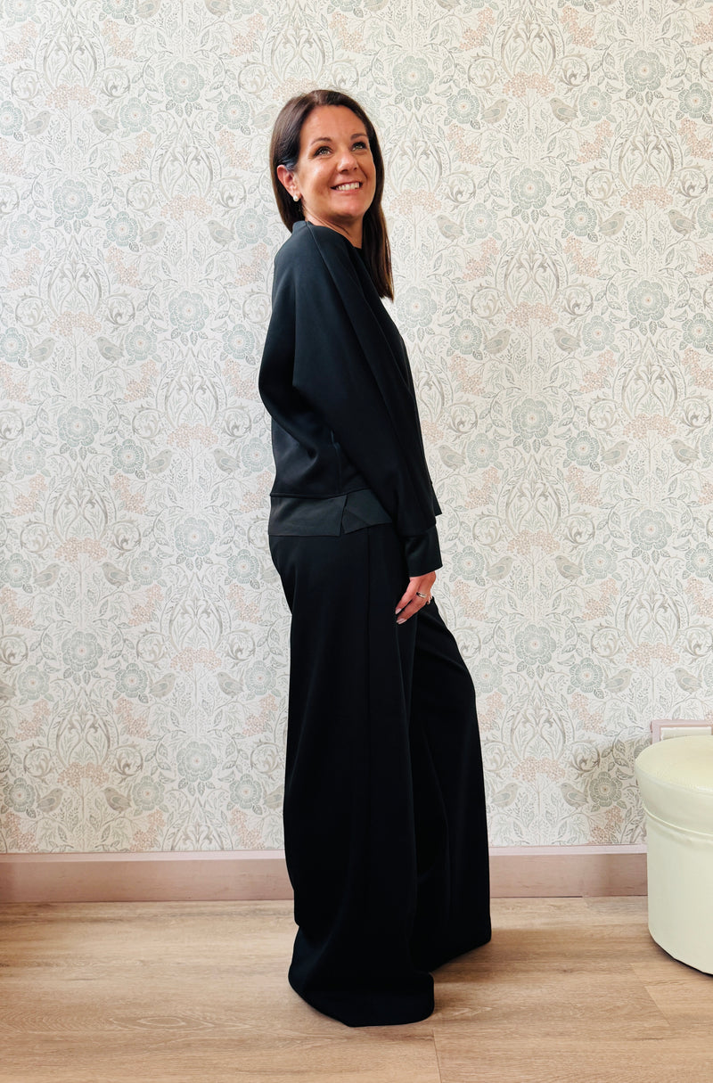 Completo da donna composto da pantaloni ampi con elastico in vita sul retro e tasche laterali; felpa con scollo tondo, manica lunga e spacchetti laterali. 