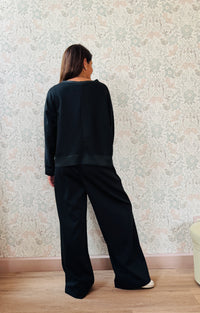 Completo da donna composto da pantaloni ampi con elastico in vita sul retro e tasche laterali; felpa con scollo tondo, manica lunga e spacchetti laterali. 