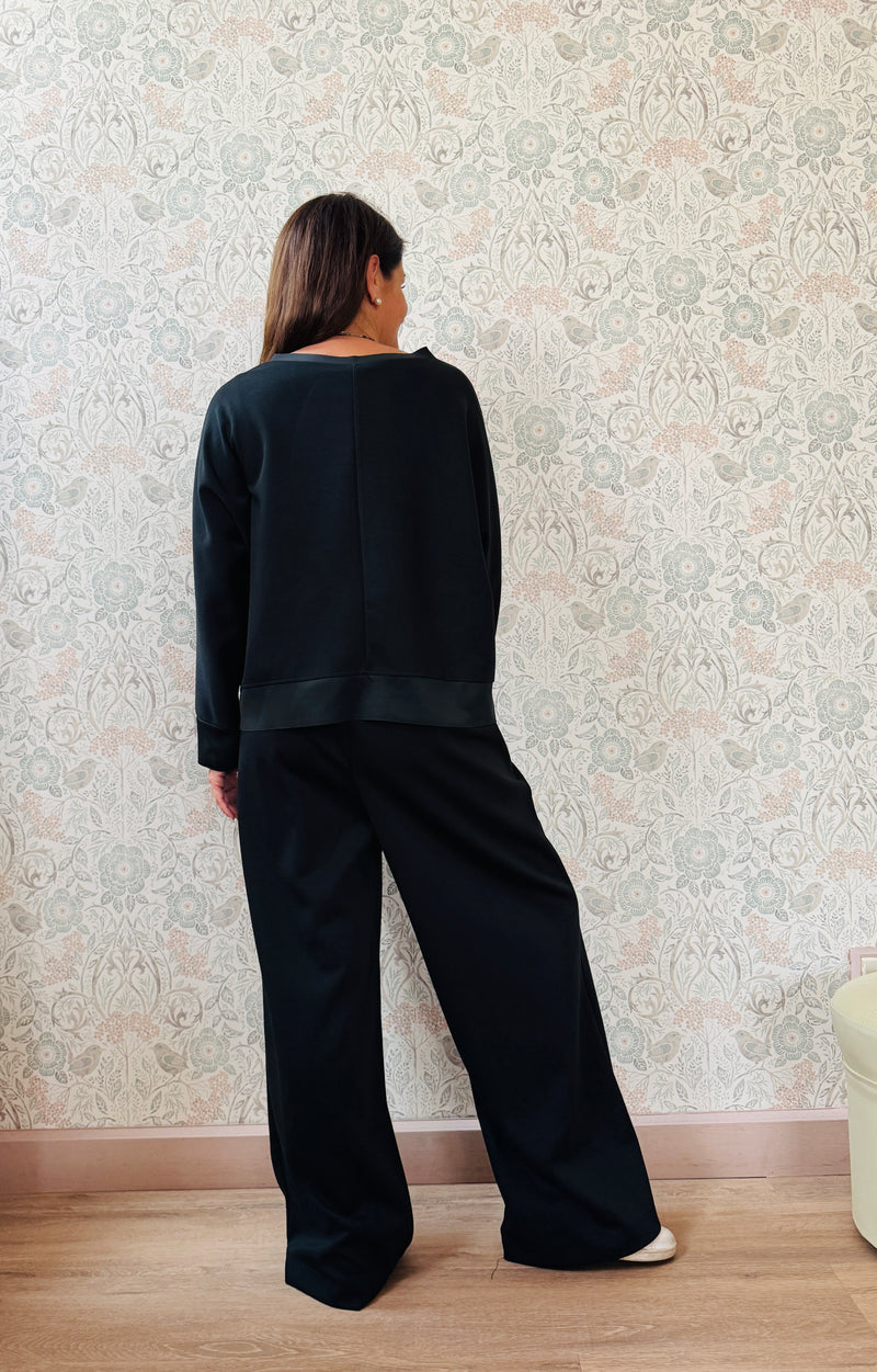 Completo da donna composto da pantaloni ampi con elastico in vita sul retro e tasche laterali; felpa con scollo tondo, manica lunga e spacchetti laterali. 
