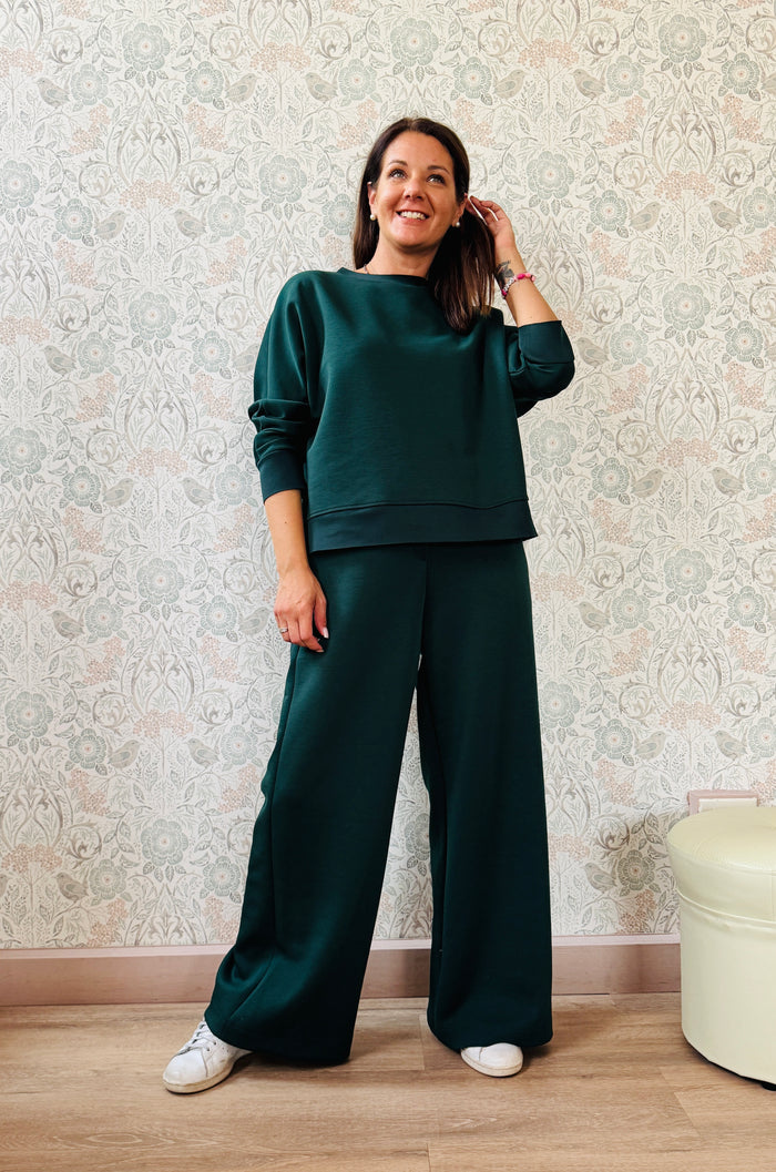 Completo da donna composto da pantaloni ampi con elastico in vita sul retro e tasche laterali; felpa con scollo tondo, manica lunga e spacchetti laterali. 