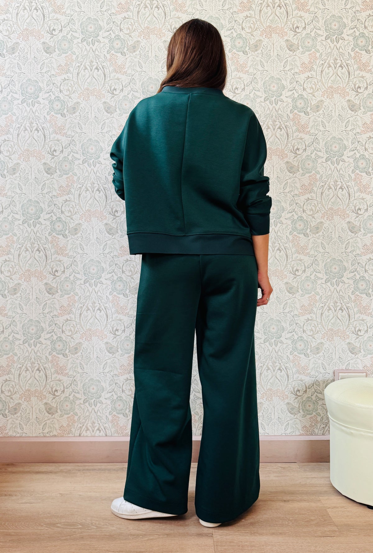 Completo da donna composto da pantaloni ampi con elastico in vita sul retro e tasche laterali; felpa con scollo tondo, manica lunga e spacchetti laterali. 