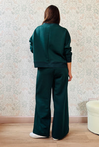 Completo da donna composto da pantaloni ampi con elastico in vita sul retro e tasche laterali; felpa con scollo tondo, manica lunga e spacchetti laterali. 