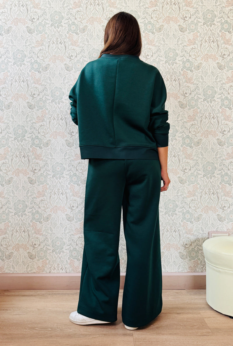 Completo da donna composto da pantaloni ampi con elastico in vita sul retro e tasche laterali; felpa con scollo tondo, manica lunga e spacchetti laterali. 